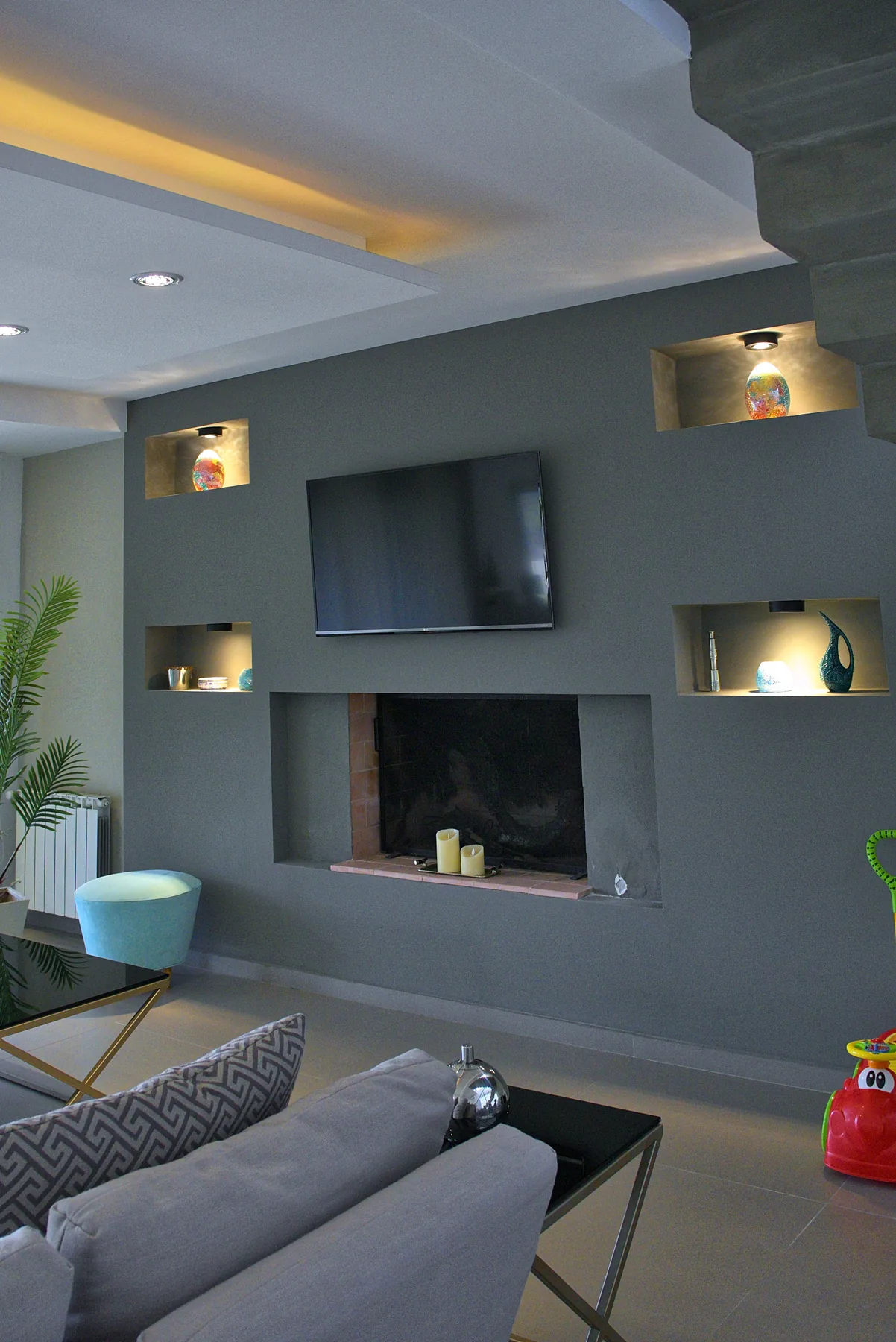 El living, con la pared del hogar y la escalera al fondo.