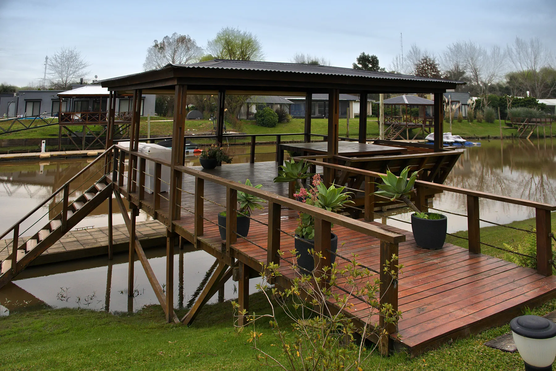El deck sobre el agua: muelle techado y flotante, unidos al parque por el puente.