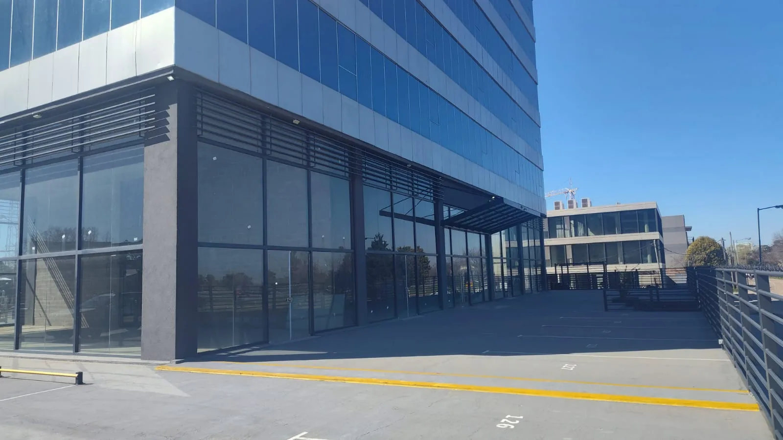 Acceso desde estacionamiento — Edificio de oficinas sobre Panamericana, unidades disponibles en pisos altos.